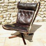 Vue de face du fauteuil Falcon Vatne Møbler années 1970 occasion, avec son coussin en cuir marron et sa structure suspendue en bois foncé.