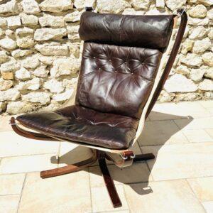 Vue de face du fauteuil Falcon Vatne Møbler années 1970 occasion, avec son coussin en cuir marron et sa structure suspendue en bois foncé.
