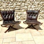 Paire de fauteuils Falcon Sigurd Ressel scandinaves 1970 avec structure en bois foncé et assise suspendue confortable en cuir noir vintage.