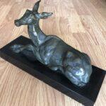 Sculpture biche bronze signée Helbert à vendre, vue de trois-quarts montrant la biche couchée sur son socle rectangulaire en marbre noir.