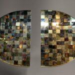 Panneau mural ovale laiton céramique Stéphane Lemeur composé de deux demi-ovales avec un damier en relief de carreaux de céramique et laiton travaillé.