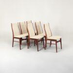 Lot de 6 chaises scandinaves vintage Johannes Andersen à vendre, vues de face, avec leur structure en bois clair et assise en tissu beige.